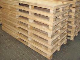 Stapel aus naturbelassenen Holzpaletten auf einem grauen Boden.